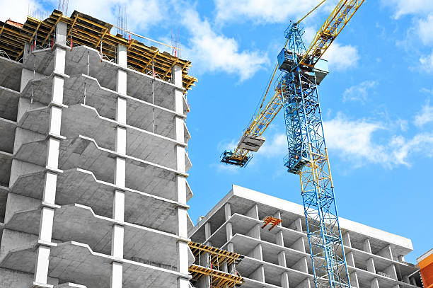 Crane and building under construction against blue sky