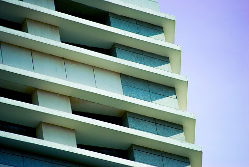 Architecture photography of a modern and geometrical facade in colors white and blue. Blue sky in the background.